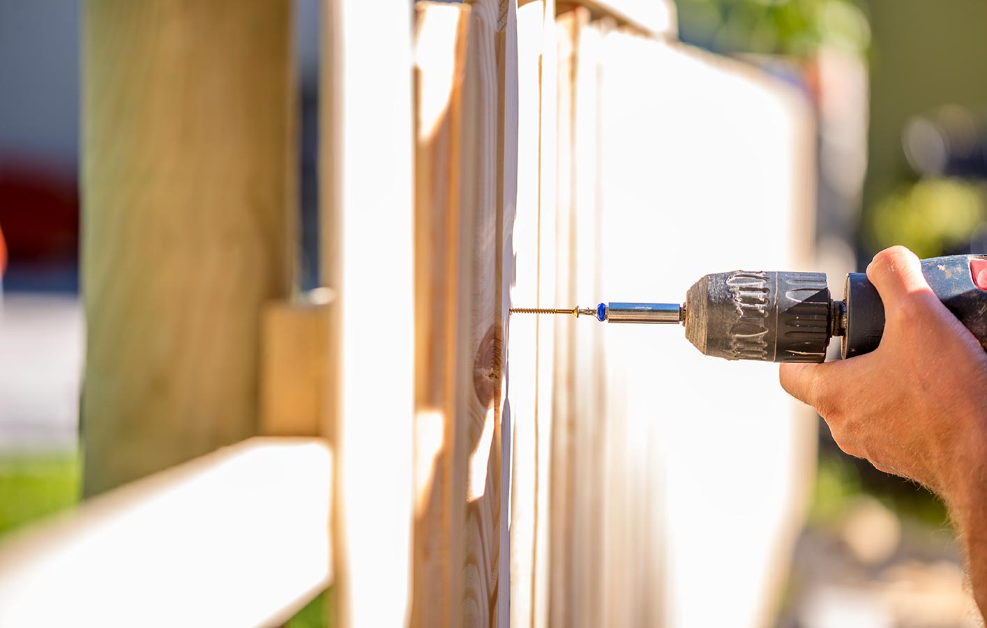 Zaunbau - Zaun montieren - Handwerkerkosten Mann baut Zaun - schraubt Brett an