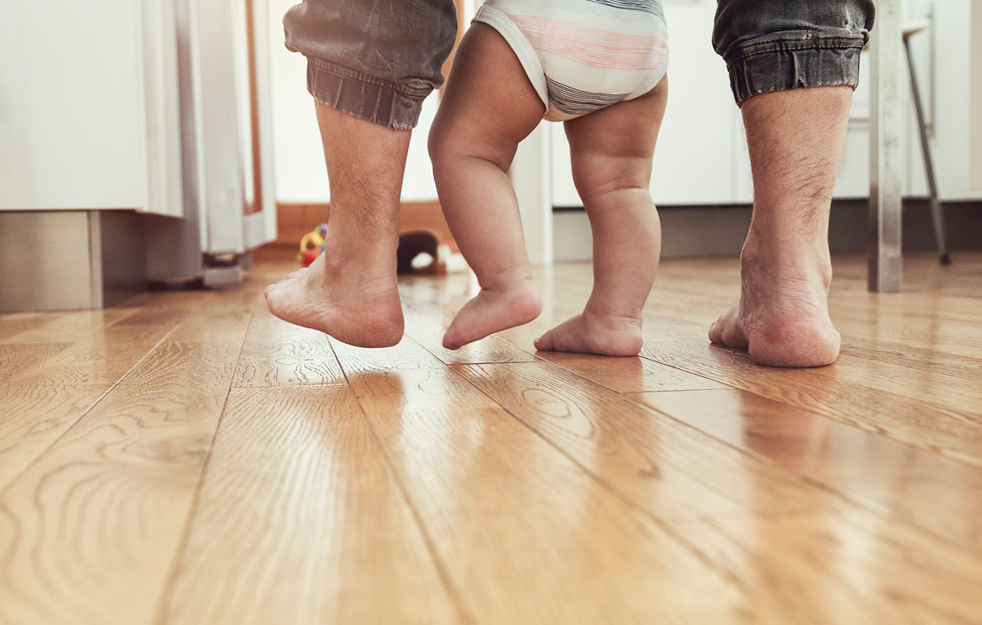 Füße von Papa und seinem Kind - laufend auf Parkettboden