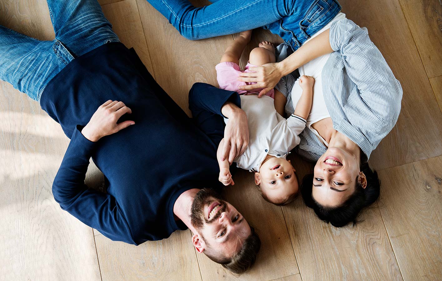 Junge Familie liegend auf dem Parkettboden